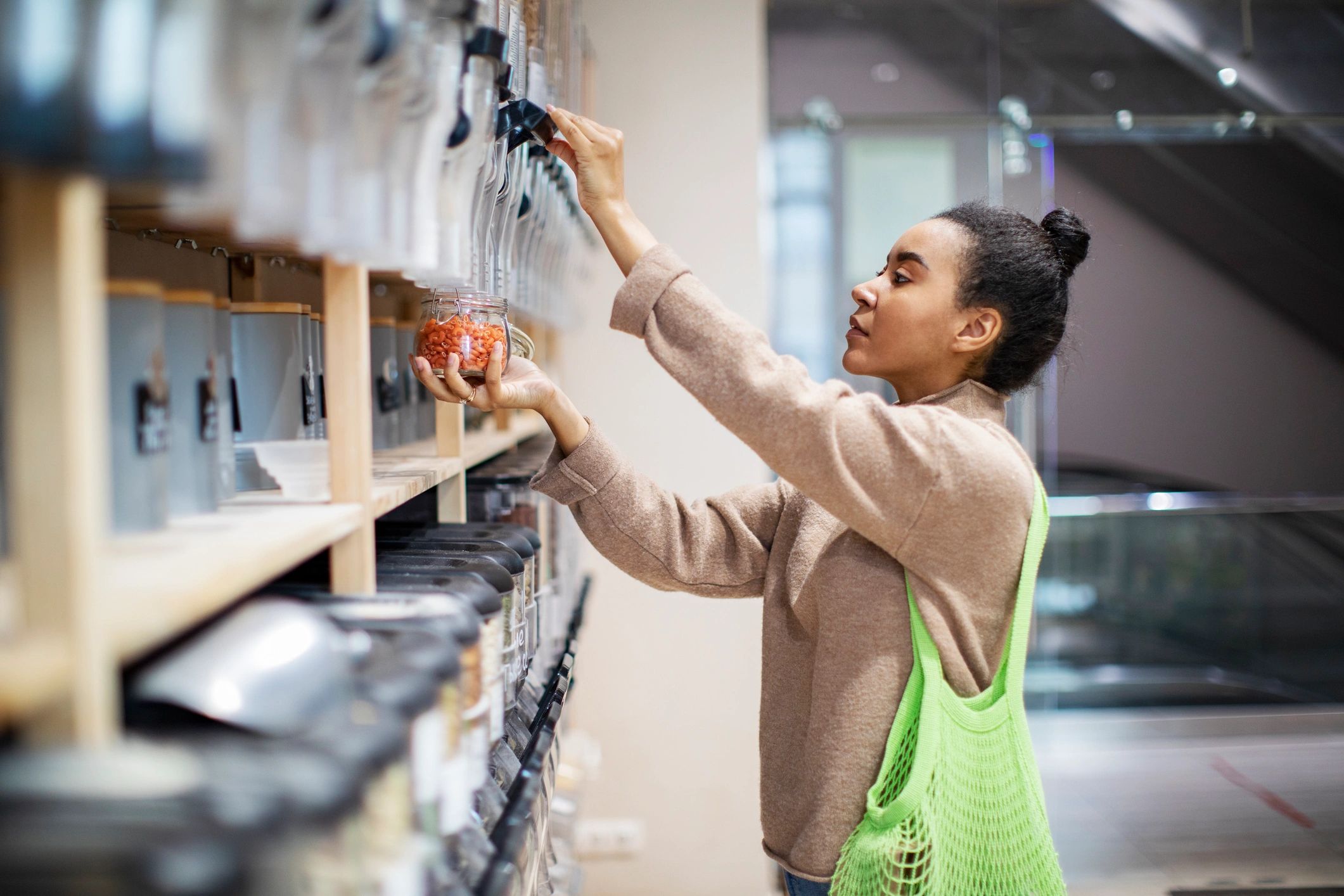 A woman refills a container at a bulk food store.